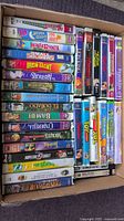 Photo of VHS movies arranged in box, showing titles such as Small Soldiers, Iron Giant, Bugs Life, Toy Story, Sound of Music, Antz, 8 Mile among others.