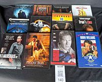 Photo showing 12 DVD movies laid out on a black surface, titles and cover art visible for identification.