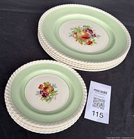 Stack of smaller plates showing the textured white edge and central fruit motif with green border