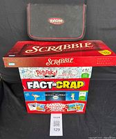 Photo showing stacked board games including Yahtzee case on top, Scrabble box, Pictureka, Fact or Crap, Trivial Pursuit, Canadian Trivia games visible below