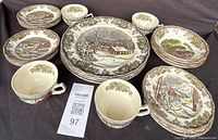 Full set showing plates, bowls, cups, and serving plate with matching winter village scenery pattern.