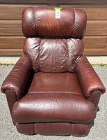 Front view of brown leather recliner chair showing cushioned back, seat and armrests with visible wear and creases