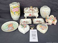Full view of all vintage ceramic decorative items including vases, trinket boxes, plates, and heart-shaped containers with various floral and character designs.
