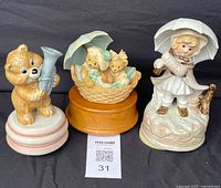 Three vintage ceramic music boxes placed side by side on a black background showing the overall set.