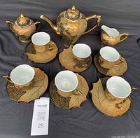 Complete tea set including teapot, sugar bowl, creamer, six cups and saucers with consistent design and wear