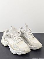 Front and top view of Adidas white running shoes showing design details, laces, brand logos, and condition.