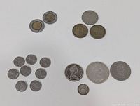 Coins arranged on a white surface showing a variety of currency including Canadian and international coins in circulated condition.
