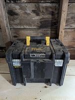 Closed Stanley Fatmax tool box showing yellow handle and silver latches on black plastic body.