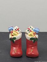 Front view of pair of vintage ceramic Christmas stocking salt and pepper shakers showing the letters S and P on the stocking base and gifts on top.