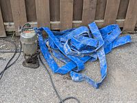 Full view of the Ponstar water pump connected with a blue fabric hose, showing the condition of both items on concrete ground.