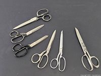 All six pairs of scissors displayed on a black surface showing size and variety.