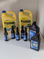 Two large yellow Prestone jugs of 50/50 antifreeze/coolant full view with smaller black bottles in front.
