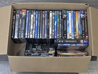 Top view of a box filled with DVDs showing multiple seasons of Supernatural and other movie titles.