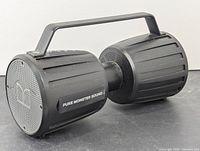 Side angled view showing the dual cylindrical speakers connected with a handle, featuring 'PURE MONSTER SOUND' label and Monster logo on speaker grills.