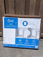 Front view of the boxed medicine cabinet showing product branding 'Ove' and model 'Mina' with key features listed on packaging.