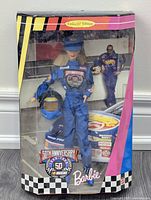 Front view of Nascar Barbie doll in original collector edition packaging showing doll in blue racing jumpsuit and helmet accessory.