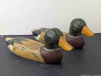 Pair of vintage wooden decorative decoy ducks sitting side by side showcasing the painted beat and body.