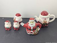Full view of the Santa Claus Christmas teapot set including two teapots, covered sugar bowl, and two salt and pepper shakers.