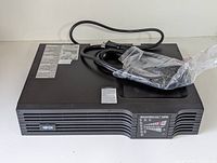 Front view of black Tripp Lite UPS with power cables on top.