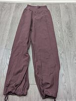 Burgundy Lululemon jogger pants with elastic waistband and drawstring ankles laid flat on floor.