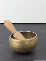Front angle of hammered brass mortar with wooden pestle resting inside