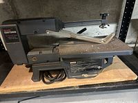 Side view of the Sears Craftsman 13 inch scroll saw showing the saw arm, table surface, and brand label.