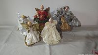Five angel tree toppers arranged on a white surface showing sizes and designs