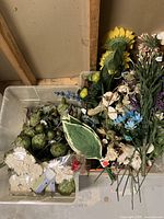Photo showing bins with an assortment of artificial floral stems including sunflowers, white flowers, blue flowers, greenery, and berry clusters.