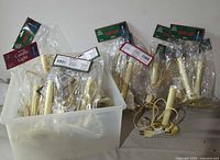 Multiple packages and one loose electric candle lights with brass colored bases on a table.