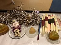 Grouped arrangement showing pillar candle, marble dome candles on plates, tapered candles, and floral garlands.
