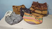 Front view of 5 different casual purses including woven wicker and fabric styles arranged on a surface.