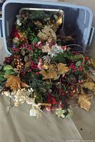 Large plastic tote filled with a mix of Christmas wreath and centrepiece sprigs showing gold, red, white, and green decorative elements
