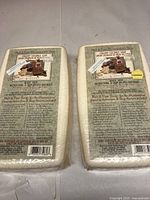 Front view of two wrapped soap bricks showing branding and instructions.