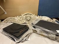 Photo showing large ceramic swag decoration and several wrapped slate pieces together on a surface