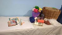 Photo showing assorted crochet thread and yarn balls in various colors and materials, knitting needles, and one large round wicker basket.