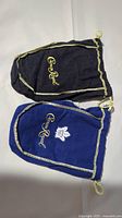 Two velvet Crown Royal bags, one black with gold trim and logo, one blue with gold trim, Crown Royal logo, and Toronto Maple Leafs logo