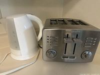 Front and side view of white electric kettle and Cuisinart stainless steel 4-slice toaster on countertop