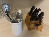 Overall front view of two knife blocks and ceramic utensil holder with kitchen tools arranged on countertop.