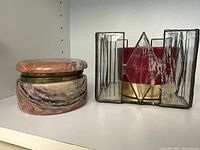 Marble trinket box and stained glass candle holder side by side on white shelf.