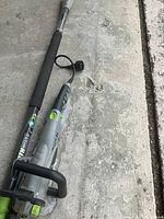 Full view of the Earthwise electric chainsaw with extension arm laid out on the ground.