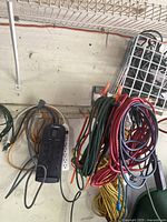 Photo showing multiple coiled electrical extension cords in various colors and a mounted black Belkin power bar.