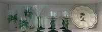 Full lot showing glassware including martini glasses, margarita glasses with green stems, frosted tumbler glasses with palm tree design, and deviled egg plate with palm tree motif