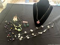 Full view of all fashion necklaces and earrings arranged on a table and display bust.
