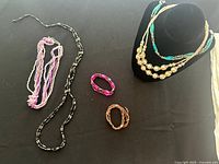 Lot overview showing several necklaces and bracelets on black surface under natural light.