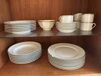 Photo showing the full set of Fitz and Floyd Palais dinnerware including 7 sandwich plates (top left), 6 cups (top right), 6 saucers (below cups), 8 soup bowls (middle left), and 8 dinner plates (bottom shelf).