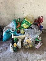 Wide view showing multiple gardening products: Miracle Gro container, various opened bags of soil, multiple bottles of weed/bug killers, and a plastic planter.