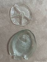 Top view showing clear glass shell-shaped plate with ridged texture and one fish plate corner.