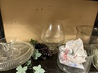 Photo showing clear glass vases and glass cake plate with decorative grape clusters and green leaf accents.