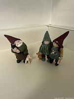 Three gnome figurines posed together on white shelf showing size and details
