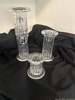 Three 'Rurik' glass candlesticks arranged on black fabric backdrop showing overall set size and design.